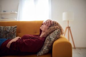 Woman with migraine laying on the couch