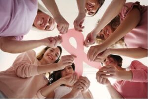 Multiple woman holding pink breast cancer ribbon together.