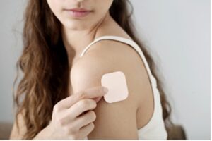 Woman applying birth control patch to arm.