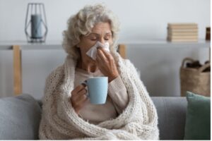 Elderly woman sick and blowing her nose.