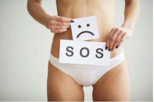 Woman holding SOS sign in front of vaginal area.